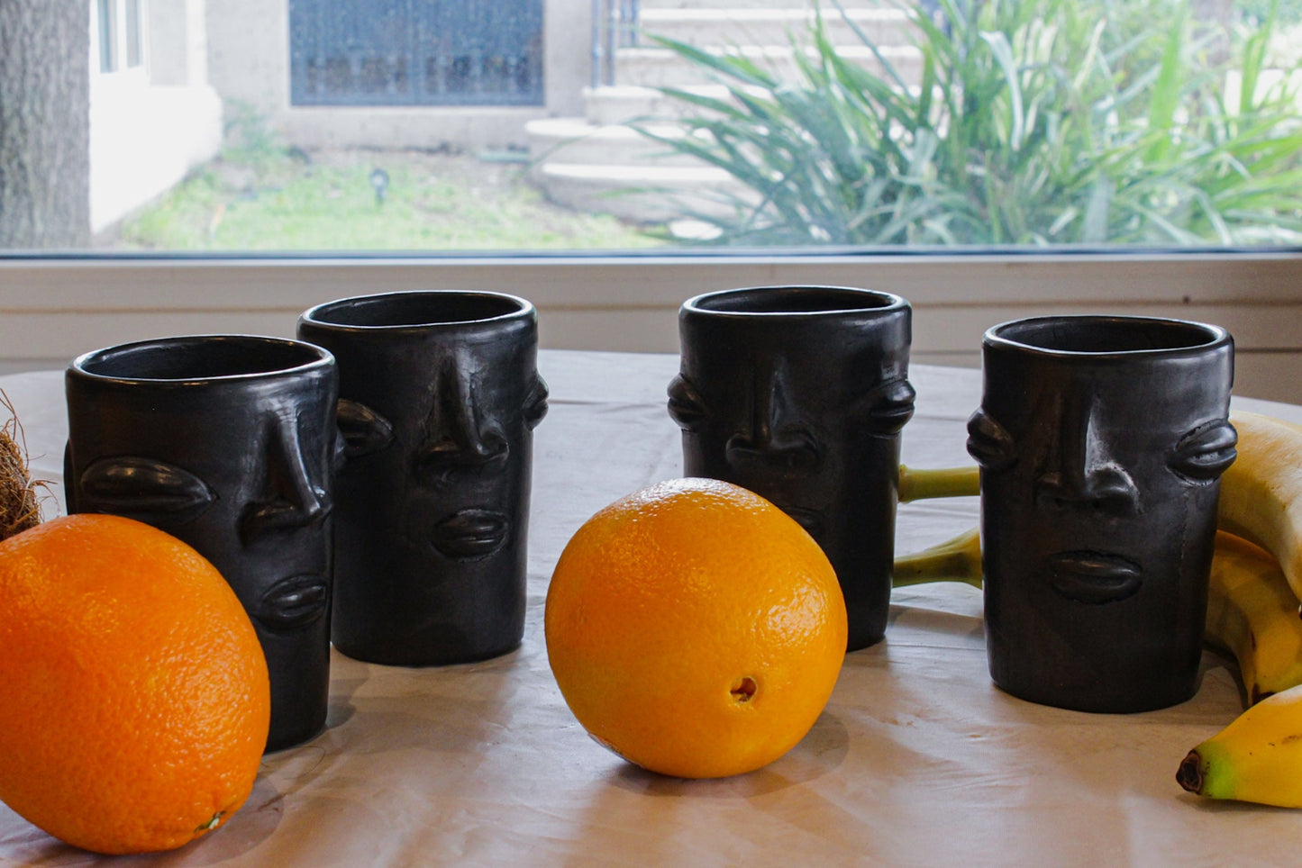 Vasos de barro negro con diseño de cara