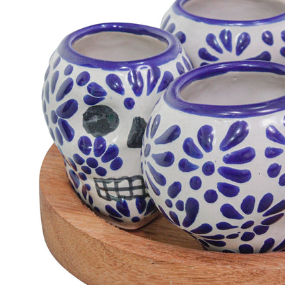 Set de 4 tequileros de talavera con forma de calavera y base de madera redonda